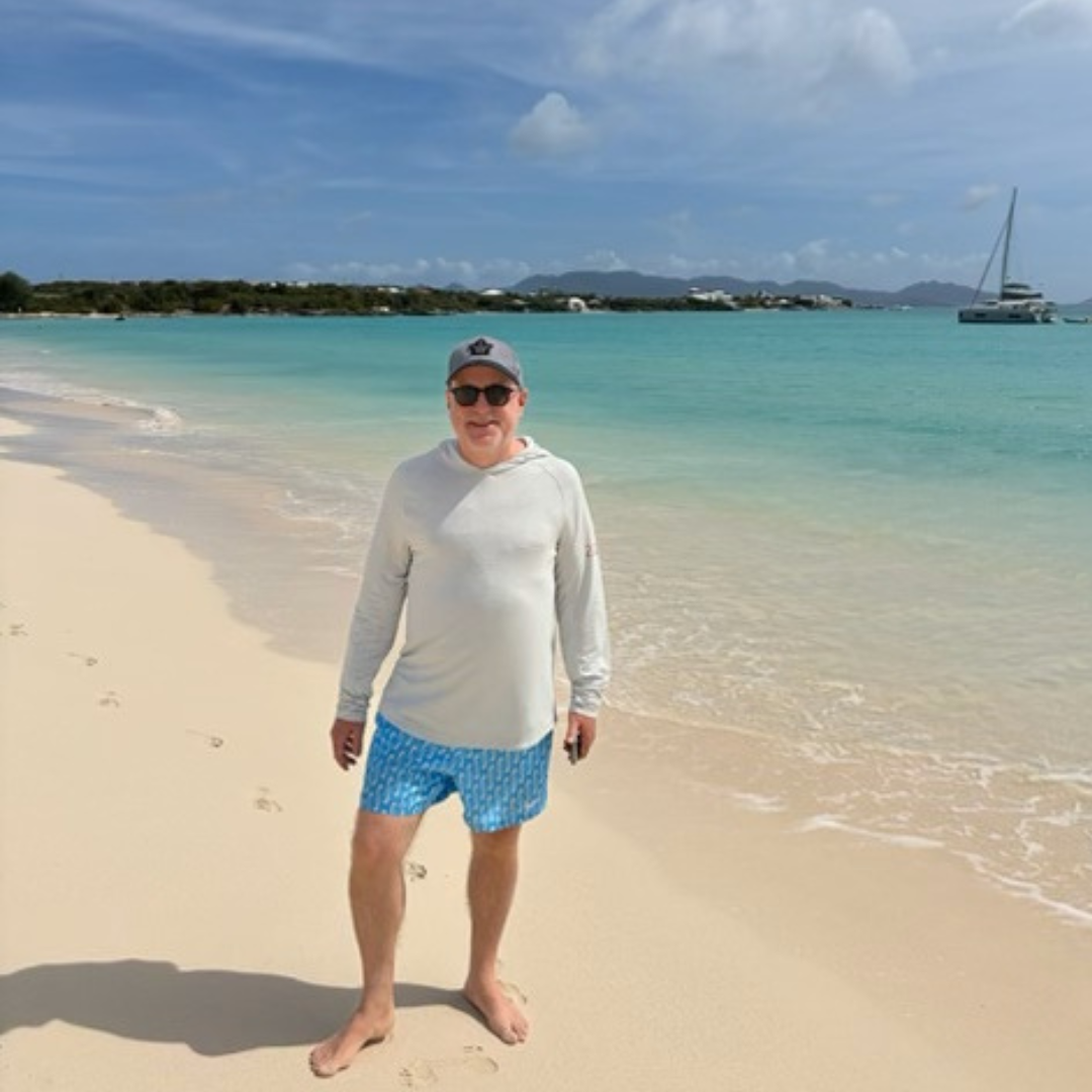 man posing on a beach in a long sleeve shirt