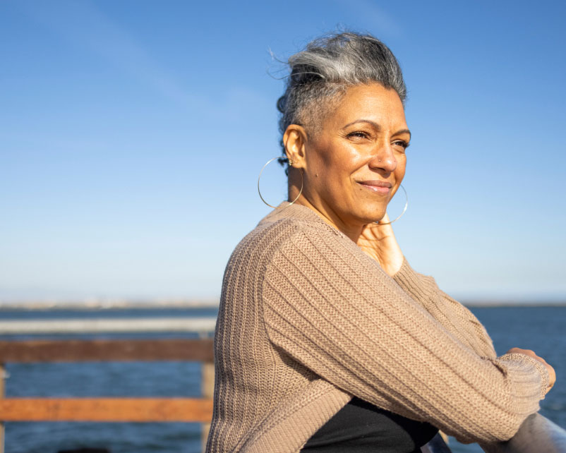 Mature woman smiling outdoors, representing community and care