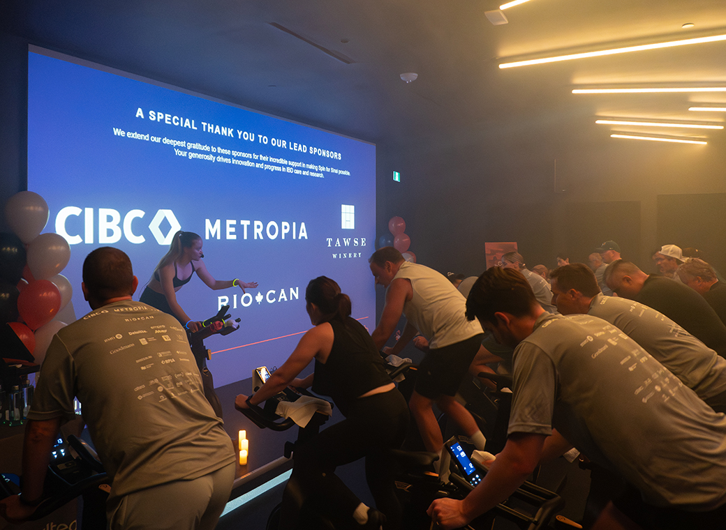 Spin class facing instructor with a screen in the background highlighting sponsors