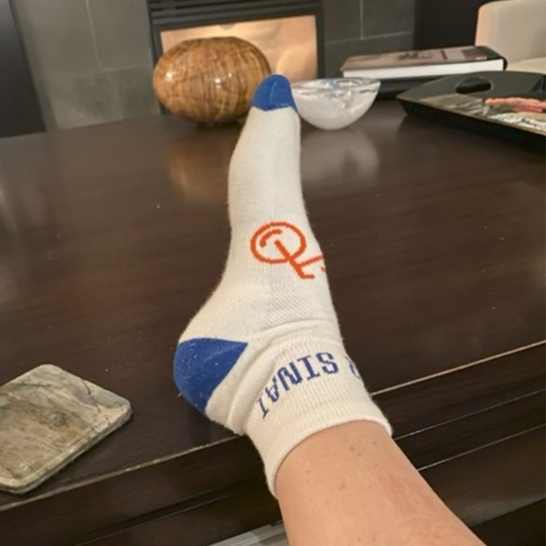 A persons leg wearing a festive sock resting on table